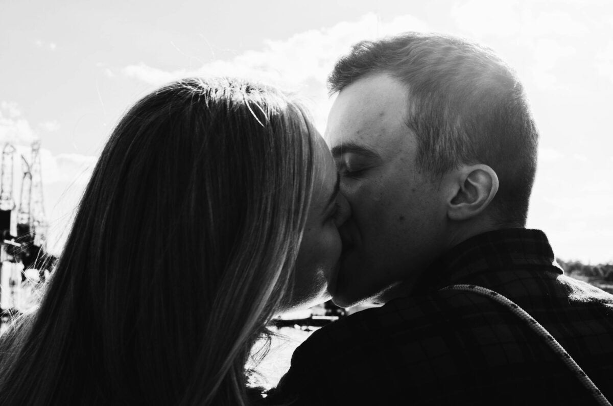 Black and white photo of a couple kissing in Poznań, showcasing love and togetherness.