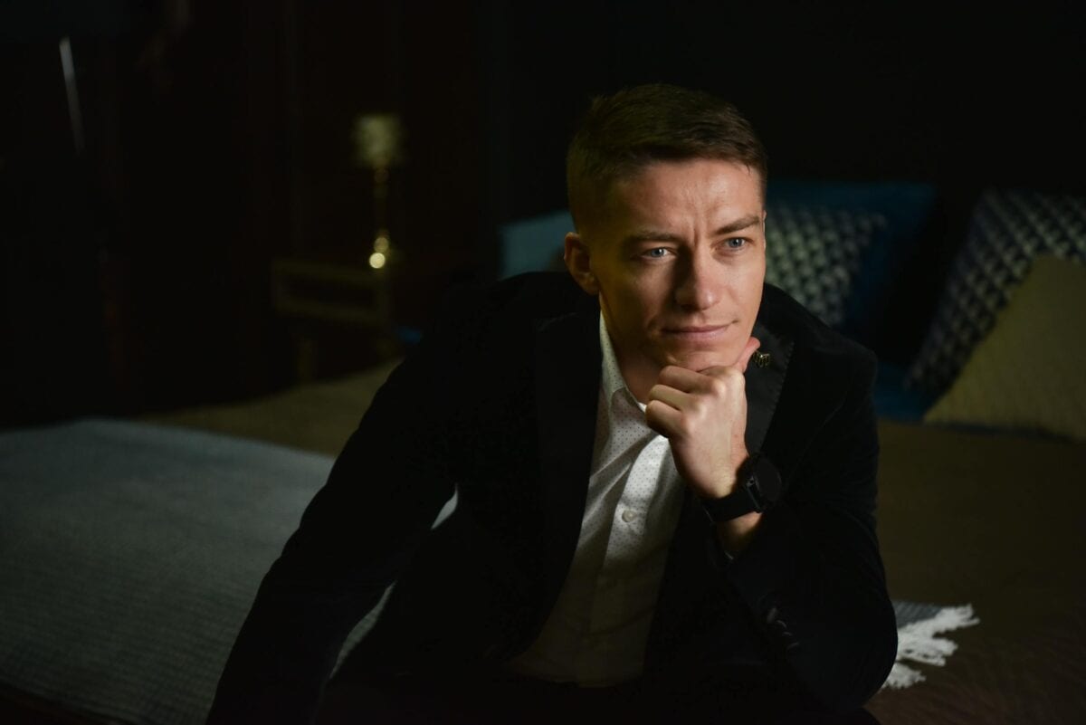 Portrait of a thoughtful man in an elegant suit, sitting indoors and posing with hand under chin.