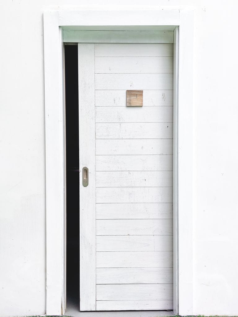 Elegant minimalist design featuring a white sliding door slightly open on a white wall, perfect for modern architecture concepts.